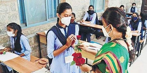 A teacher welcomes a student with a rose, at a government PU college in Malleswaram, in Bengaluru on Monday (Pic: Shriram BN/Express)