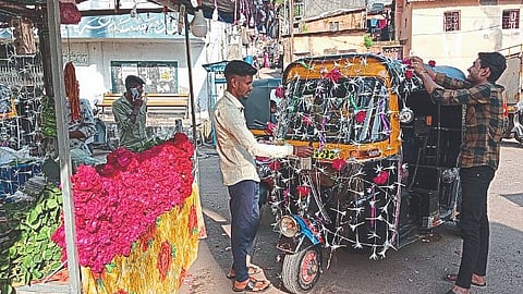 A flower seller and a rickshaw puller decorating a rickshaw on the occasion of Lakshmi Pujan