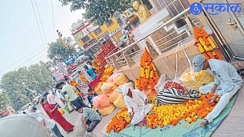 Businessmen selling flowers near the Mahatma Gandhi statue at Mosam Pul Chowk here