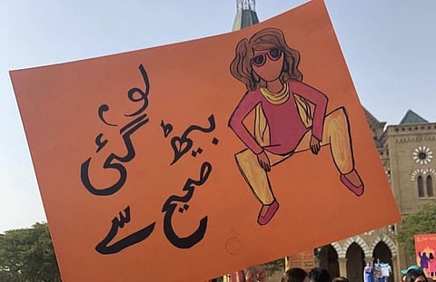 A placard at Aurat March 2019. The Urdu text reads, "Here you go: I am sitting correctly now". Photo: Facebook