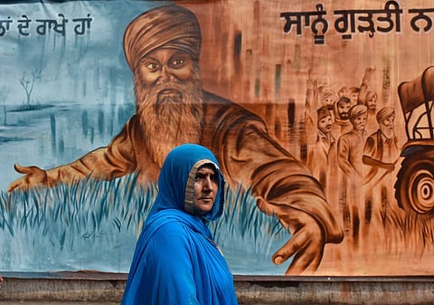 A woman walks past a mural at the Singhu border protest site of the 2021 farmers protests in New Delhi. Neha Dixit draws readers into understanding not just of the personal experiences of inequality but of the intractable reasons for its continuation among India’s working-class minority women.