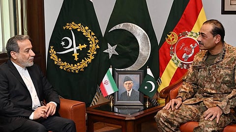 Pakistan’s army chief, Asim Munir, dressed in military uniform (left) meeting Iran’s foreign minister, Abbas Araghchi dressed in a white shirt and black suit (right). Both are seated on either side of a table with a photo of Pakistan founder Mohammed Ali Jinnah and a flag of the Islamic Republic of Iran. In the background are large flags of Pakistan and the Pakistan Armed Forces.