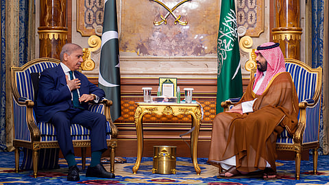 Saudi Crown Prince Mohamed bin Salman, sitting on the right, meets with Pakistan's Prime Minister Shehbaz Sharif sitting on the left in Jeddah. The setting is official, with the flags of Pakistan and Saudi Arabia behind them as well as a richly patterned backdrop.