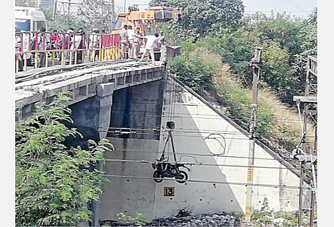 பாலத்தில் இருந்து விழுந்த இரு சக்கர வாகனத்தை மீட்கும் போலீஸார்.