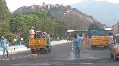 பழநி பேருந்துநிலையத்தில் கிருமிநாசினி தெளிக்கும் பணியில் ஈடுபட்டுள்ள தூய்மை பணியாளர்கள்.