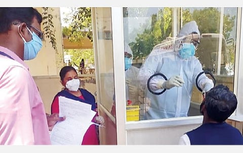 காரைக்கால் அரசு பொது மருத்துவமனையில் கண்ணாடி கூண்டுக்குள் இருந்தவாறு பரிசோதனைக்கான மாதிரி எடுக்கும் மருத்துவக் குழுவினர்.
