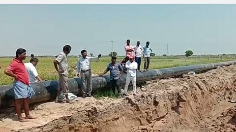 பள்ளம் தோண்டியதால் கடந்து செல்ல முடியாமல் ஒரு கரையில் நின்று கொண்டு மற்றொரு கரையில் நிற்கும் ஒப்பந்த நிறுவனத்தாரிடம் வாக்குவாதம் செய்யும் விவசாயிகள்.