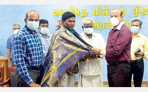 ‘நீட்’ தேர்வில் 562 மதிப்பெண்கள் பெற்ற அரசுப் பள்ளி மாணவர் குணசேகரனை வேலூர் மாவட்ட ஆட்சியர் சண்முகசுந்தரம் சால்வை அணிவித்து பாராட்டினார். அருகில், மாவட்ட முதன்மை கல்வி அலுவலர் மார்ஸ், மாணவரின் தந்தை ராஜேந்திரன் உள்ளிட்டோர். படம்: வி.எம்.மணிநாதன்.