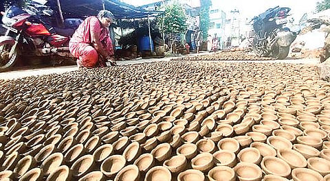 வேலூர் சூளைமேடு பகுதியில் களிமண்ணாலான அகல் விளக்குகளை செய்து வெயிலில் உலர்த்தும் பணியில் ஈடுபட்டுள்ள பெண். படம்: வி.எம்.மணிநாதன்
