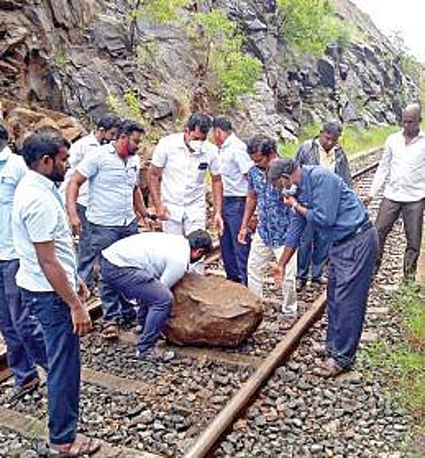 திண்டுக்கல் மாவட்டம் முருகன்பட்டியில் ரயில் தண்டவாளத்தில் பாறை விழுந்ததால் பாதிவழியில் நின்ற வைகை எக்ஸ்பிரஸ். (அடுத்த படம்) ரயில் தண்டவாளத்தில் விழுந்த பாறையை அகற்றும் பணியில் ஈடுபட்ட பணியாளர்கள், பயணிகள்.