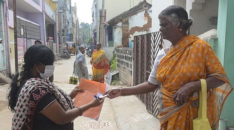 வேலூரில் வீடு, வீடாகச் சென்று பொங்கல் பரிசுத் தொகுப்பு பெறுவதற்கான டோக்கனை விநியோகம் செய்யும் ரேஷன் கடைப் பணியாளர்.