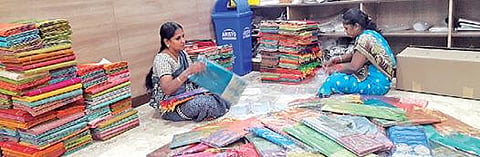 விற்பனைக்காக கொண்டு செல்ல பேக்கிங் செய்யப்படும் நெகமம் காட்டன் மற்றும் பட்டு ரக சேலைகள்.