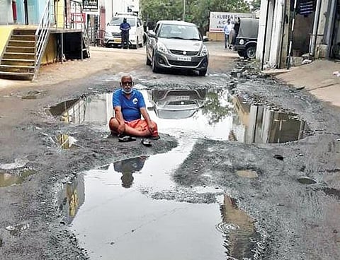 கழிவுநீர் மத்தியில் அமர்ந்து போராட்டத்தில் ஈடுபட்ட சமூக ஆர்வலர்.