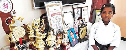 கராத்தே மற்றும் சிலம்பக் கலைகளில் தான் பெற்றுள்ள பரிசுக் கோப்பைகள் மற்றும் சான்றிதழ்களுடன் மேட்டூரைச் சேர்ந்த சிறுமி அழகினி.
