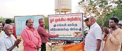 சிவகங்கை அருகே தெக்கூர் கிராம எல்லையில் ‘எங்கள் வாக்கு விற்பனைக்கு அல்ல’ என்ற அறிவிப்பு பலகையை வைத்துள்ள கிராம மக்கள்.