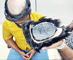 தலையில் பொருத்திக்கொள்ளும் ‘விக்’கில் தங்கம் எப்படி மறைத்து வைக்கப்பட்டிருந் தது என்பதை காட்டும் அதிகாரி.