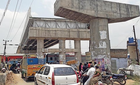திண்டுக்கல்-சிலுவத்தூர் சாலை ரவுண்ட் ரோட்டில் ரயில்வே மேம்பாலம் பணி காரணமாக பேருந்துகள் செல்லாத நிலையில் அமைக்கப்பட்டுள்ள பயணில்லாத நிழற்கூரை.