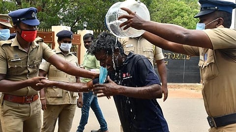தூத்துக்குடி ஆட்சியர் அலுவலகம் முன்பு உடலில் பெட்ரோல் ஊற்றி தீக்குளிக்க முயன்ற ஆனந்தன் மீது போலீஸார் தண்ணீரை ஊற்றி தடுத்து நிறுத்தினர். படம்: என்.ராஜேஷ்