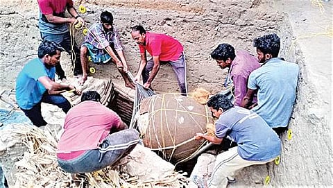 தூத்துக்குடி மாவட்டம் ஏரல் அருகே கொற்கையில் அகழாய்வுப் பணியின்போது சுமார் 5 அடி உயரமுள்ள குதிர் கண்டுபிடிக்கப்பட்டது. அதை கயிறு கட்டி பணி யாளர்கள் வெளியே எடுக்கின்றனர்.