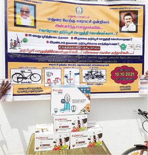 மதுரை மாவட்ட ஆட்சியர் அலுவலகத்தில் தடுப்பூசி போட்டுக்கொள்வோருக்கு வழங்கப் படுவதாக அறிவித்துள்ள சைக்கிள், குக்கர், மிக்ஸி உள்ளிட்ட பரிசுப் பொருட்கள்.