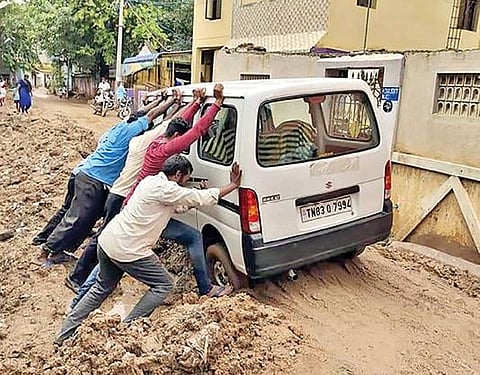 ஆம்பூர் ஏ-கஸ்பா பகுதியில் சாலையில் சிக்கிய வாகனத்தை அப்புறப்படுத்தும் பணியில் ஈடுபட்ட பொதுமக்கள்.