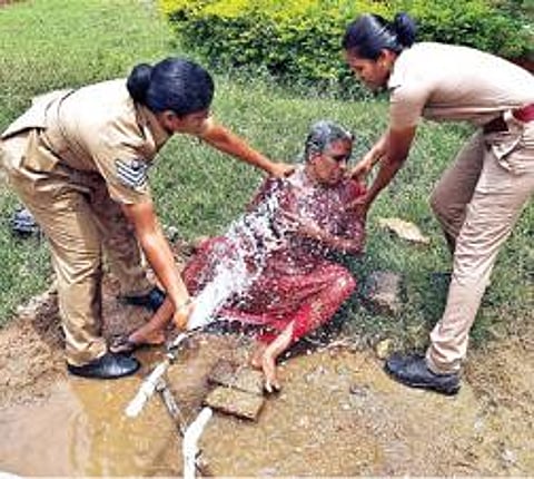 தற்கொலை மிரட்டல் விடுத்த மூதாட்டியின் உடலில் தண்ணீரை ஊற்றிய பெண் காவலர்கள். படம்: இரா.தினேஷ்குமார்.