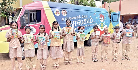 கோவை கெம்பட்டி காலனி மாநகராட்சிப் பள்ளிக்கு வந்த நடமாடும் நூலகத்தில் எடுத்த புத்தகங்களுடன் மாணவ, மாணவிகள்.