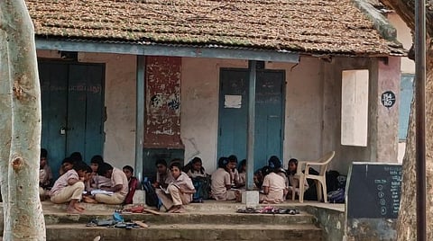 அங்குச்செட்டிப்பாளையம் உயர்நிலைப்பள்ளியில் பழுதடைந்த வகுப்பறைக் கட்டிடத்தில் அமர்ந்திருக்கும் மாணவர்கள்