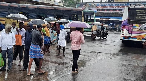 திருவண்ணாமலை மத்திய பேருந்து நிலையத்தில் கொட்டும் மழையில் பேருந்துக்காக காத்திருக்கும் பயணிகள்.