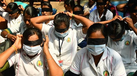 கண்களில் கருப்புத் துணியைக் கட்டியபடி சேலத்தில் போராட்டத்தில் ஈடுபட்டுவரும் பணி நீக்கம் செய்யப்பட்ட ஒப்பந்த செவிலியர்கள்.