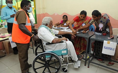 ஈரோடு கிழக்கு தொகுதியில் சக்கர நாற்காலியில் வாக்களிக்க வந்த முதியவர்