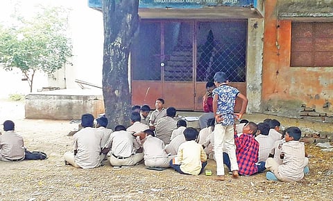 கள்ளக்குறிச்சி அரசு ஆண்கள் மேல்நிலைப் பள்ளி மாணவர்கள் மரத்தடியில் அமர்ந்து படிக்கின்றனர்.