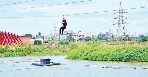 கோவை உக்கடம் பெரியகுளத்தில் பொருத்தப்பட்டுள்ள சாகச விளை யாட்டுக்கான கட்டமைப்பில் தொங்கியபடி செல்லும் இளைஞர்.