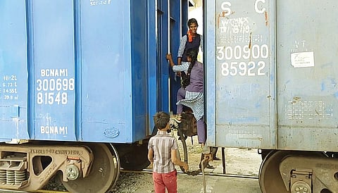 சரக்கு ரயில் மீது ஏறி பள்ளிக்கு செல்லும் மாணவ, மாணவிகள்.