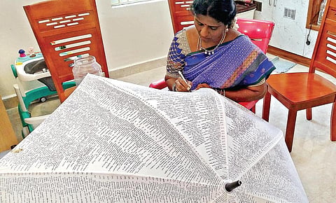குடையில் திருக்குறளை எழுதும் ஆசிரியர் உமாராணி.