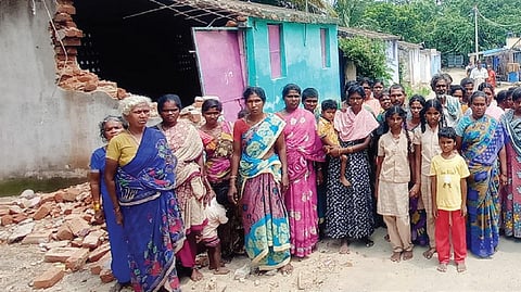பர்கூர் அருகே ஒப்பதவாடி காளியம்மன் கோயில் இருளர் காலனியில் அண்மையில் பெய்த மழைக்குச் சுவர் இடிந்து விழுந்த தொகுப்பு வீட்டின் அருகே திரண்ட அப்பகுதி பெண்கள்.