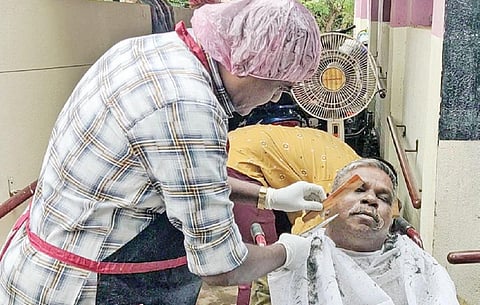 சிவகங்கை தாய் இல்லத்தில் மாற்றுத் திறனாளிக்கு முடிதிருத்தம் செய்யும் வேல்முருகன்.