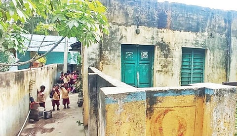 பாகலூரில் ஊராட்சி அலுவலகம் அருகே இடிந்து விழும் நிலையில் ஆபத்தான நூலக கட்டிடத்தையொட்டி உள்ள அங்கன்வாடி மையத்தின் வெளியே உள்ள குழந்தைகள்