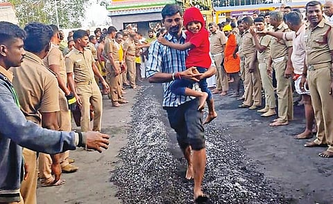 பாரியூர் கொண்டத்து காளியம்மன் கோயில் திருவிழாவில், குழந்தையுடன் குண்டம் இறங்கி நேர்த்திக்கடன் செலுத்திய பக்தர்.