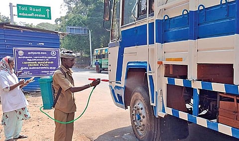 கேரளாவிலிருந்து வரும் வாகனங்களுக்கு குமுளியில் கிருமி நாசினி தெளித்த பணியாளர்.