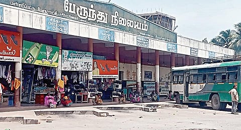 பள்ளிப்பட்டு பேருந்து நிலையத்தில் அமர இருக்கைகள் இல்லாததால், தரையில் அமர்ந்துள்ள பயணிகள்.