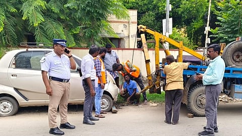 போக்குவரத்துக்கு இடையூறாக சாலையோரம் கேட்பாரற்று கிடக்கும் வாகனத்தை அப்புறப்படுத்தும் மாநகராட்சி பணியாளர்கள்.