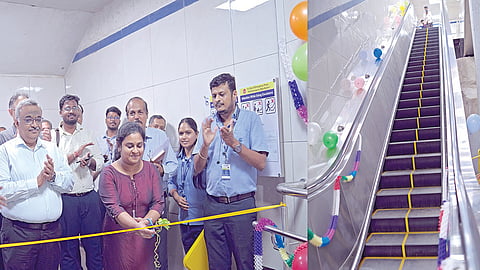 மெட்ரோ ரயில் நிலையத்தில் புதியதாக அமைக்கப்பட்ட நகரும் படிக்கட்டை திறந்து வைக்கும் பெண் பயணி. அருகில் மெட்ரோ ரயில் நிறுவன அதிகாரிகள், பணியாளர்கள்.