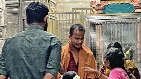 பழநி திருஆவினன்குடி கோயிலில் கேரள பக்தர்களுக்கு பிரசாதம் வழங்கும் பெண் இடைத்தரகர்.
