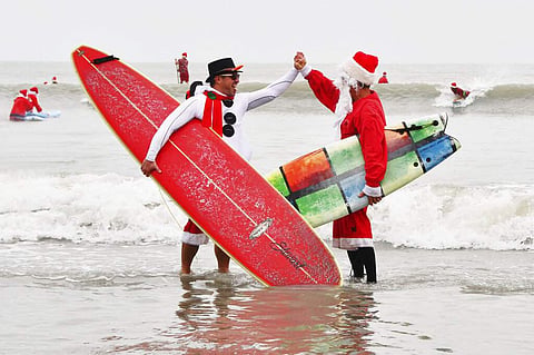 Surfing Santas (Malcolm Denemark/Florida Today via AP)