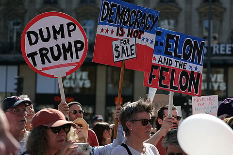 Protesters hold placards during a "Hands Off!" demonstration called by the Democrats Abroad organisation against US President's administration and his advisor Tesla CEO in Paris, on April 5, 2025.