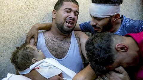 Palestinian Mahmoud Mikdad mourns holding the body of his 21-month-old child Yamam, killed in the Israeli