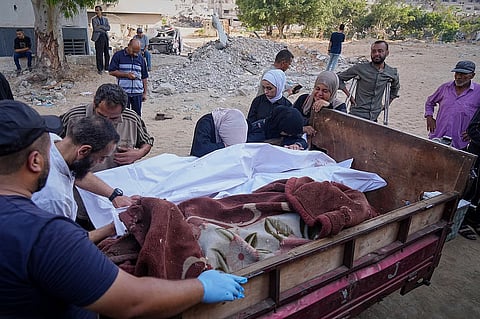 Palestinian women mourn over the wrapped bodies of Palestinians killed in Israeli army strikes as they arrive at Shifa