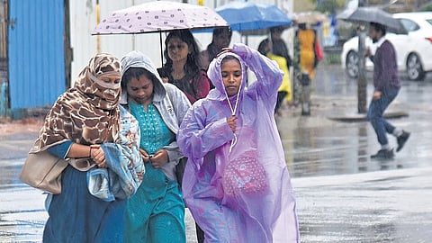 Raincoats and umbrellas come out as heavy rain pounds the city on Monday evening.