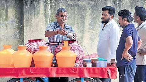 People line up to buy buttermilk and ragi ambli to cool their body amid rising temperatures on Ulsoor Road on Sunday